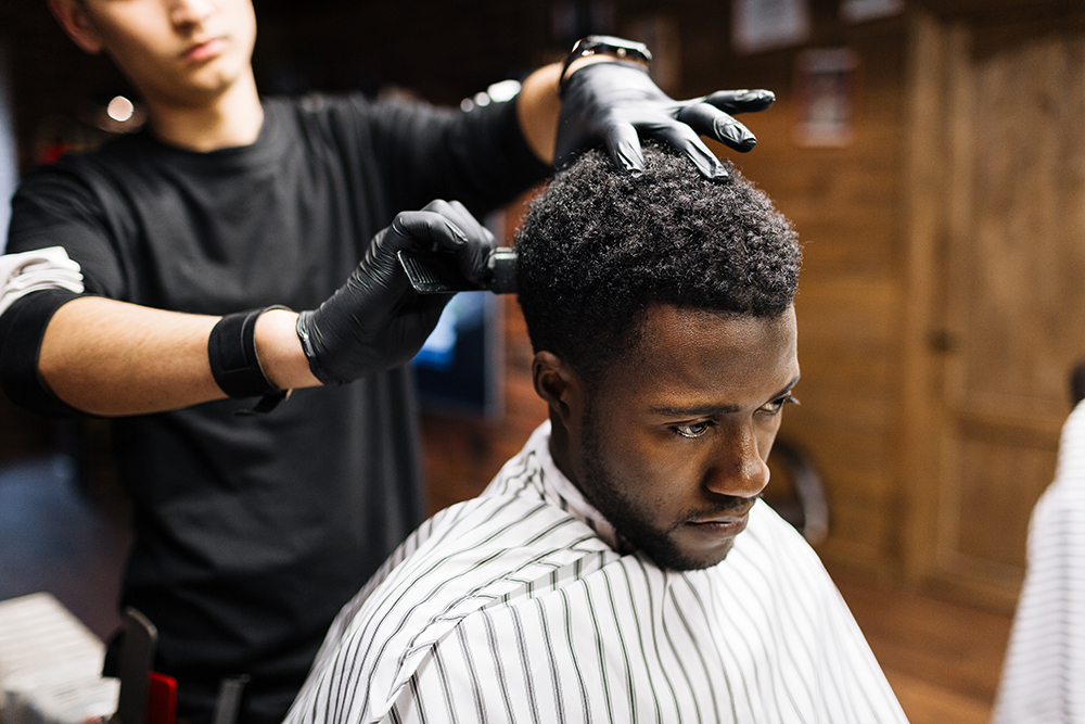 Barbero recortando a un hombre de color